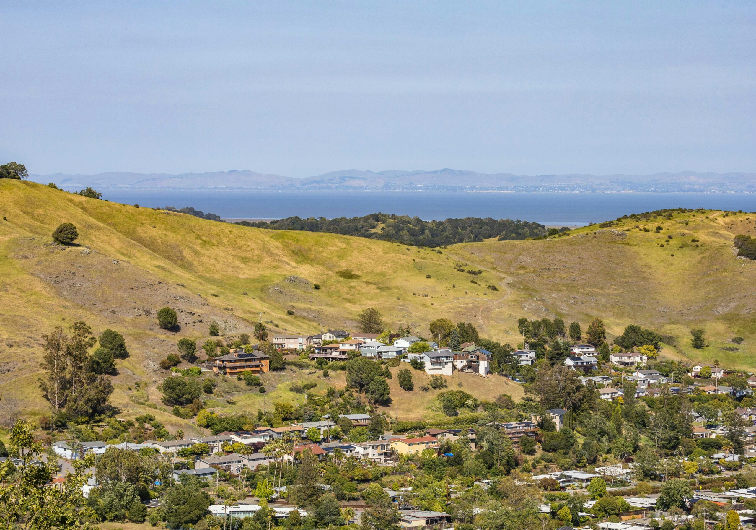 Scenic aerial view of rural landscape with hills, houses, and distant water.
